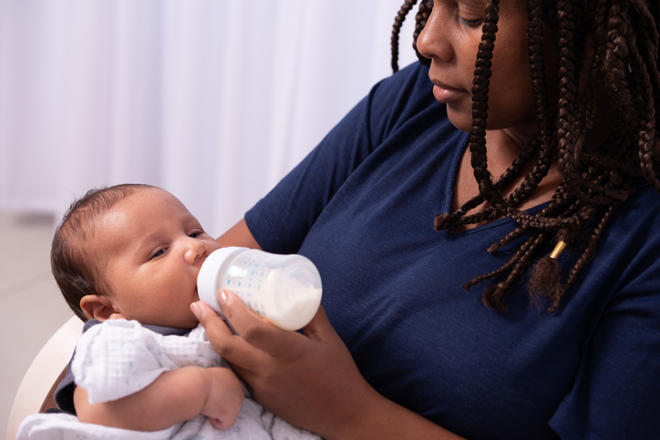 brother feeding little sister with milk or cereal with a bottle Stock Photo